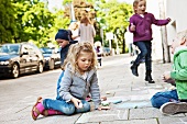 Children drawing with chalk on pavement