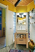 Badezimmerecke mit modernem Waschtisch aus Holz und Aufbaubecken vor weiss gefliesten Wänden