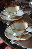 Two antique white china teacups with gold trim