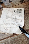 Old, crumpled document and glass quill pen on antique, natural wood table