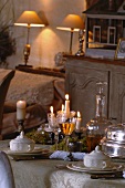 Festively set table in candlelight atmosphere and table lamps on shelf in background