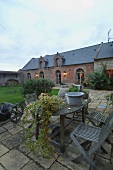 Twilight in garden courtyard of French country manor with wooden table and folding chairs on old stone flags