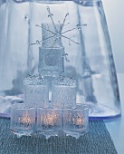 Pyramid of tealight holders made of crystal-style glass and decorative snowflake ornament in front of glass vase