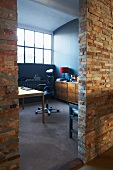 Stone-clad partition wall of loft studio apartment with view of desk and office chair beyond