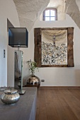 Table lamp with cubic fabric lampshade on half-height cabinet opposite wall with picture in rustic wooden frame in foyer