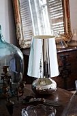 Vintage candlestick, garden shears, silver table lamp and demijohn on wooden table