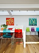 Farbige Kunststoff Stühle an weißem Esstisch gegenüber Wand mit modernen Bildern