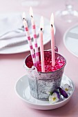 Candles and pink decorative pebbles in little metal bucket decorating table