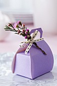 Lilafarbene Geschenkverpackung in Taschenform mit Blüten dekoriert