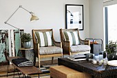 Rustic coffee table in front of armchairs with scatter cushions next to vintage standard lamp in modern setting