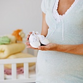 Schwangere Frau mit Babyschuhen
