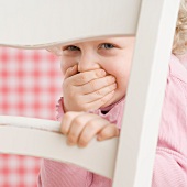 Portrait of child looking through a chair