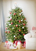 Dekorierter Weihnachtsbaum & Geschenke neben Sofa