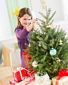 Girl (8-9) hanging decorations on Christmas tree