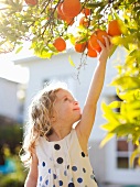 Happy young girl (4-5) reaching for fresh orange