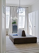 View through open door of double-sided sofa in front of white wardrobes in dressing room with traditional ambiance
