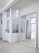 Large framed mirror leaning against wall next to doors with latticed glass panels in foyer