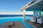 Set tables on floating wooden deck next to pool with view of ocean