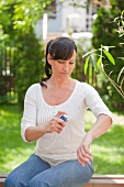 Frau besprüht ihren Arm mit einem Spray