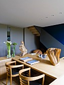 Wohnraum mit Holztisch, Armlehnstühlen & Skulpturen aus Holz