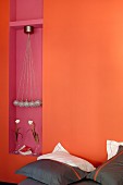 Pillows with dark brown covers against orange wall with mauve niche