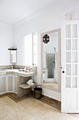 Oriental bathroom with tiled washstand; masonry shower cubicle and Moroccan pendant lamp reflected in mirror