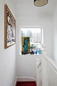 Framed artworks and lattice window in white stairwell