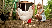 Mädchen schaut Hühnern auf dem Bauernhof zu