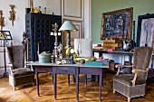 Herrschaftlicher Raum mit rustikalem Tisch und Polstersesseln in künstlerischem, werkstattähnlichem Ambiente