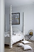Kissen auf Teppichboden vor Bett mit weiss lackierten gedrechselten Bett-Säulen