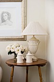 Vase of white roses, table lamp and vintage, china jars on side table