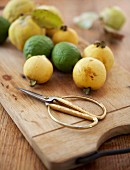 Fresh fruit and gilded kitchen scissors on chopping board