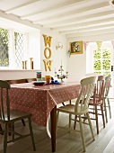 Dining room with spotted tablecloth and antique, hand-painted wooden chairs