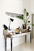 Retro table lamp next to ceramic figurines and vase of palm leaves on vintage table below collection of scissors hanging on wall