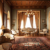 Lavish salon with elaborately carved coffered ceiling, elegant Baroque furniture and exquisite floral carpet in blue and red
