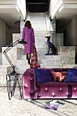 Purple sofa on ground floor in front of woman and dog statue on stone staircase