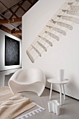 Retro chair, side table, umbrella stand and rug on grey plastic floor in corner of room with graphic mural and tapestry
