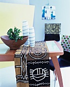 Fifties-style beech wood table with glass top decorated with ethnic table cloth, wooden bowl and vases