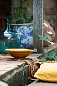 Yellow ceramic dish on stone step with terracotta tiles