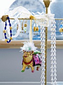 Tierfigur aus Metall neben Ohrringen und Halsketten auf Schmuckständer gehängt