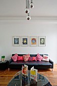 Glas Couchtisch gegenüber schwarzer Ledercouch an Wand mit Warhol Siebdrucken in minimalistischem Ambiente