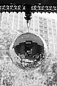 Disco ball with mosaic mirrors hanging from decorative metal strip