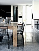 Solid wooden table and plexiglass chairs in dining area opposite kitchen counter