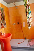 Designer bathroom with orange walls in shower area and orange pedestal sink