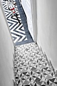 Staircase with traditional, Moroccan-style patterned tiles merging into modern, graphic, black and white pattern of courtyard floor tiles
