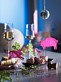 Hand-crafted animal figures and petits fours on dishes, with glasses of sparkling wine in the background