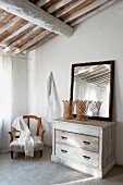 Mirror on vintage chest of drawers and armchair below Mediterranean roof structure on corner of bedroom