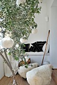 Olive tree branch with woolen balls and little sheep stools in front of a brick seating niche with black and white Kilim pillows