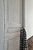 Black and white scarf hanging from the handle of an artisan, white lacquer, wood door