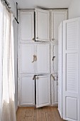 White lacque, r built in cupboard with natural wood door pulls in a narrow room